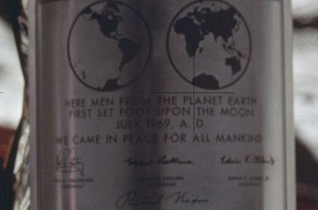 The plaque on the lunar module's leg, with two hemispheres of Earth and lines of engraved text, from a small, soft photograph