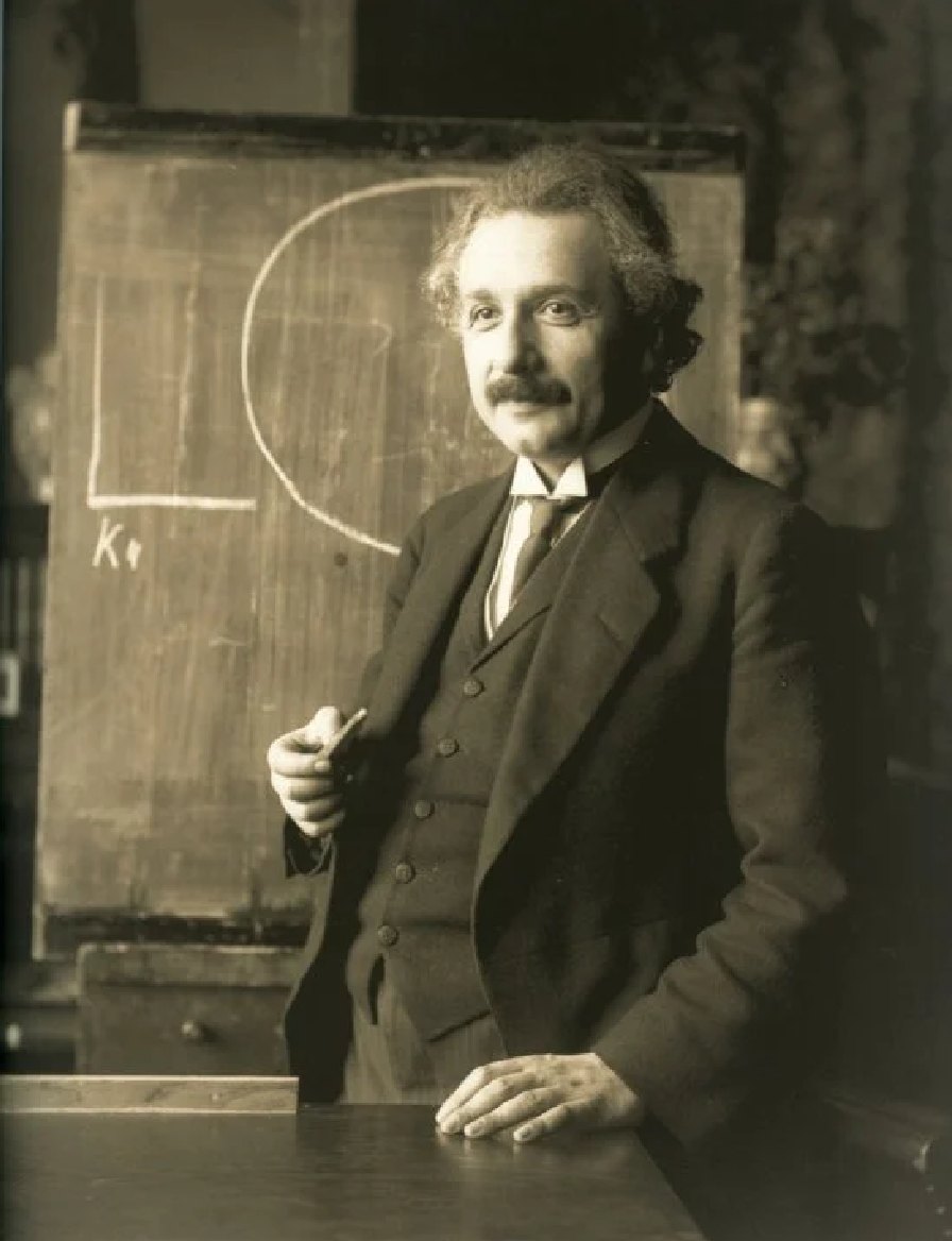 Albert Einstein at a blackboard in a faded sepia photograph